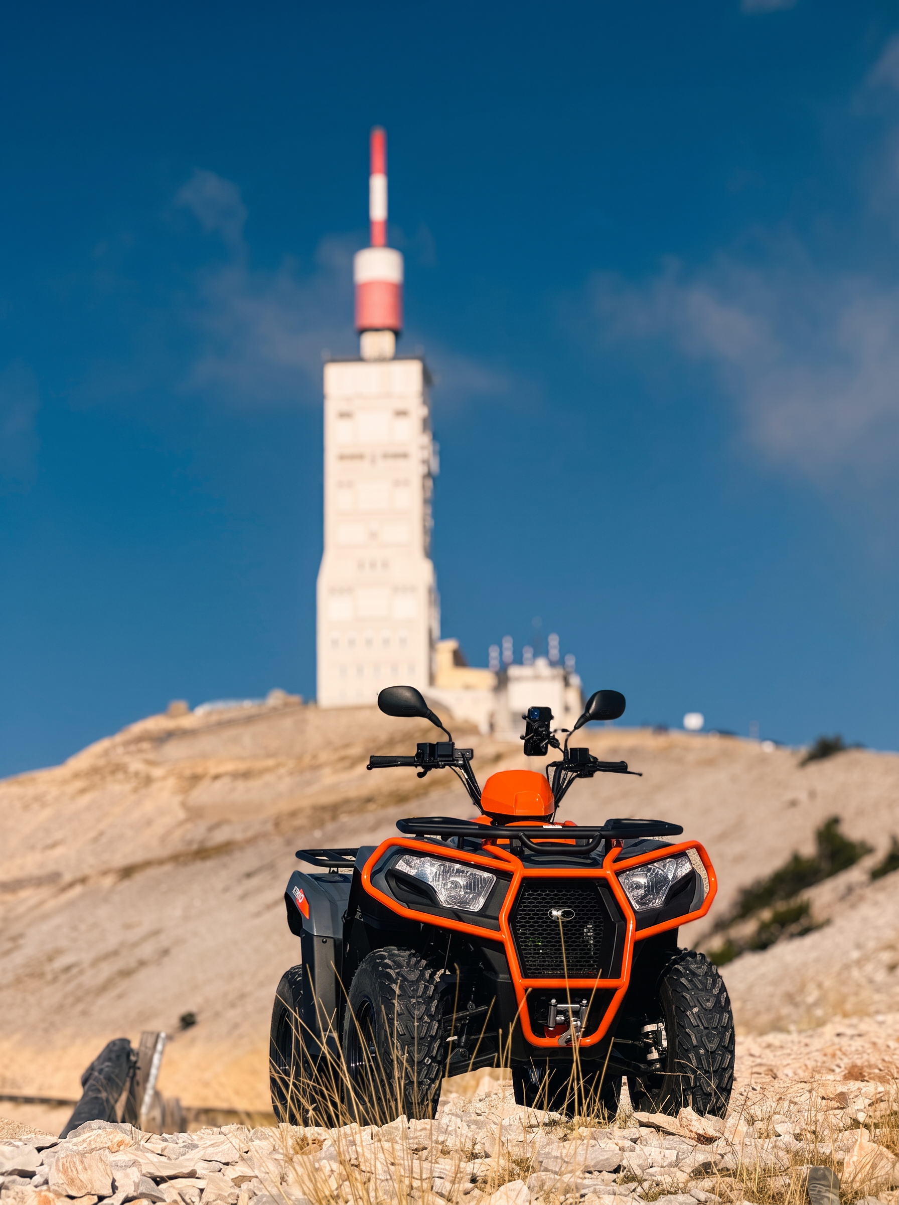 Quad Kymco orange au sommet du Mont Ventoux devant la tour de l'observatoire